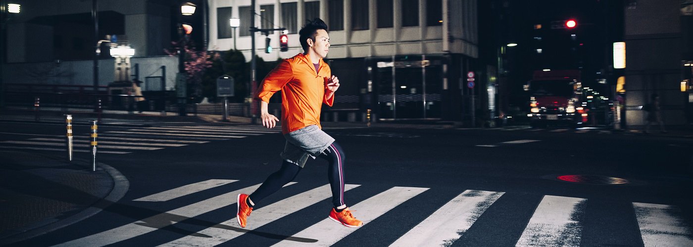 Person running across a city crosswalk at night, highlighting the importance of joint health